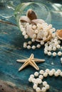 The pirate`s treasure - white pearls and shells on blue wooden background, vintage fashion