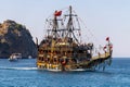 Pirate ship with relaxing tourists onboard in harbour of Mediterranean sea on mountains background