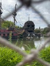 Pirate ship sailing in a tranquil body of water near a rocky shoreline with lush green grass Royalty Free Stock Photo