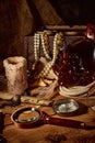 Pirate still life with candle, compass, dark rum in a skull bottle and old papers