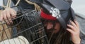 Pirate in tricorn hat and wig with dreadlocks takes cage with cute dachshund puppy, looks in there and starts to babble