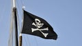 The pirates flag waving on a blue sky background Royalty Free Stock Photo