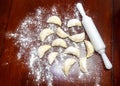 Pirogues ,pierogis, verenik, on wooden table with rolling pin and wheat flour scattered