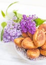Piroshki - russian baked puff pastry with cabbage fillings and bouquet of lilacs. Traditional russian cabbage stuffed baked pastry Royalty Free Stock Photo