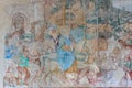 Close-up on ancient fresco representing a saint man riding a horse along other horsemen outside a medieval town