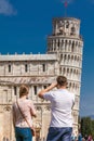 Young couple of tourists taking pictures of the famous Leaning Tower of Pisa Royalty Free Stock Photo