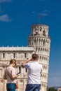 Young couple of tourists taking pictures of the famous Leaning Tower of Pisa Royalty Free Stock Photo