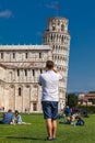 Young male tourist taking pictures of the famous Leaning Tower of Pisa Royalty Free Stock Photo