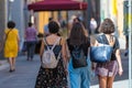 Three women with backpacks are walking along the narrow streets of the old town. Rear view