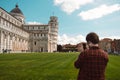 Pisa, Italy - March 18, 2023: Back view of travel tourists man making photo in front of leaning tower Pisa, Italy. Royalty Free Stock Photo