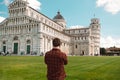 Pisa, Italy - March 18, 2023: Back view of travel tourists man making photo in front of leaning tower Pisa, Italy. Royalty Free Stock Photo