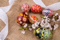 Pisanki with cherry blossom and white ribbon on sackcloth. Easter eggs in ethnic style. Easter eggs on canvas. Royalty Free Stock Photo