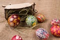 Pisanki with a wooden antique cart and hay on sackcloth. Easter eggs in ethnic style. Easter eggs on canvas.