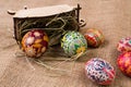 Pisanki with a wooden antique cart and hay on sackcloth. Easter eggs in ethnic style. Easter eggs on canvas.