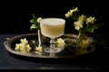 pisco cocktail garnished with flowers and greenery on a tray