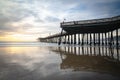 Pismo Beach pier at sunset with beautiful sun reflections on sandy beach, and beautiful cloudy sky on background, California centr Royalty Free Stock Photo