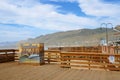 Pismo Beach sign on the pier and wooden boardwalk. Beautiful view of Pismo Beach city with mountains and cloudy sky on background Royalty Free Stock Photo