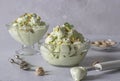 Pistachio ice cream with nuts in two transparent glass ice-cream bowl on a light gray background. Royalty Free Stock Photo