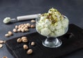 Pistachio ice cream with pistachio nuts glass ice-cream bowl on a dark background, horizontal format