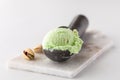 Pistachio ice cream in a scoop on a small marble slab