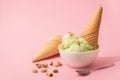 Pistachio Ice Cream in a white bowl and waffle cone, pink background, copy space. Summer cooling desserts