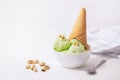 Pistachio Ice Cream in a white bowl and waffle cone, white background, copy space. Summer cooling desserts