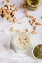 Pistachio matcha latte in a cup and nuts in a bowl and on the table top and vertical view Royalty Free Stock Photo