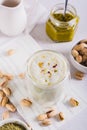 Pistachio matcha latte in a cup and nuts in a bowl and on the table vertical view Royalty Free Stock Photo