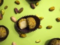 Pistachio white chocolate truffle cut in two halves in a brown candy wrapper on a light green background. Royalty Free Stock Photo