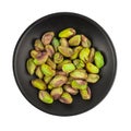 Pistachios in a black plate isolated on white background.