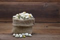 Pistachios nuts in burlap sack on wooden background.