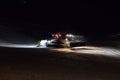 A snow groomer compacting ski runs at night
