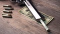 A pistol with bullets and money dollars lies on wooden the table. Revolver close-up