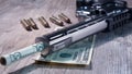 A pistol with bullets and money dollars lies on wooden the table. Revolver close-up