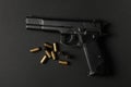 Pistol and traumatic bullets on black background