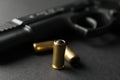 Pistol and traumatic bullets on black background