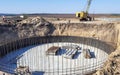 The pit in the ground with a round foundation with reinforcement at the beginning of construction.