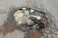 Pit on the road with stones and bricks, top view. Pavement damage