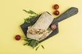 Pita bread roll with a threaded shrimp ring, fresh lettuce and cherry tomatoes on a wooden board on a yellow background Royalty Free Stock Photo