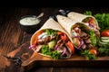 Pita wrapped Greek gyros on a dark wooden background with copy space