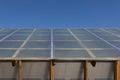 The pitched roof of a barn, outbuildings, a barn made of polycarbonate against a blue sky. Bottom view