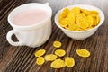 Pitcher with yogurt, bowl with corn flakes, scattered cornflakes on wooden table Royalty Free Stock Photo