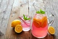 Pitcher of pink lemonade with filled glass on rustic wood