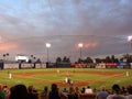 Pitcher throws pitch towards batter at dusk