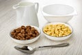 Pitcher with yogurt, empty bowl, cereal breakfasts with chocolate and caramel in bowls, spoon on wooden table Royalty Free Stock Photo