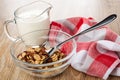 Pitcher with yogurt, napkin, spoon with cereal breakfast with chocolate and caramel in bowl on wooden table