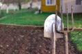Pitchfork and shovel lying on the fence in the village against the backdrop of a country house and garden in the summer