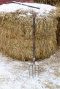 Pitchfork stands near snow-covered haystack in country in winter