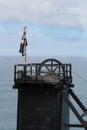 The pithead of a Cornish tin mine showing the main lifting pulley, with a Cornish nationalist Kernow flag Royalty Free Stock Photo