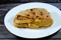 A pitta flatbread filled with mixture of potatoes fried fingers, mashed fava beans, fried aubergine, Egyptian falafel green burger